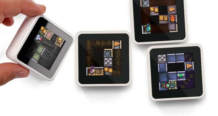 Hand holding a Sifteo cube next to other cubes displaying connected pixel map tiles